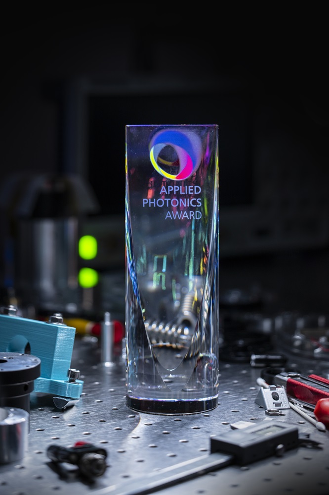 A glass  trophy stands on a work surface in the laboratory, surrounded by tools.